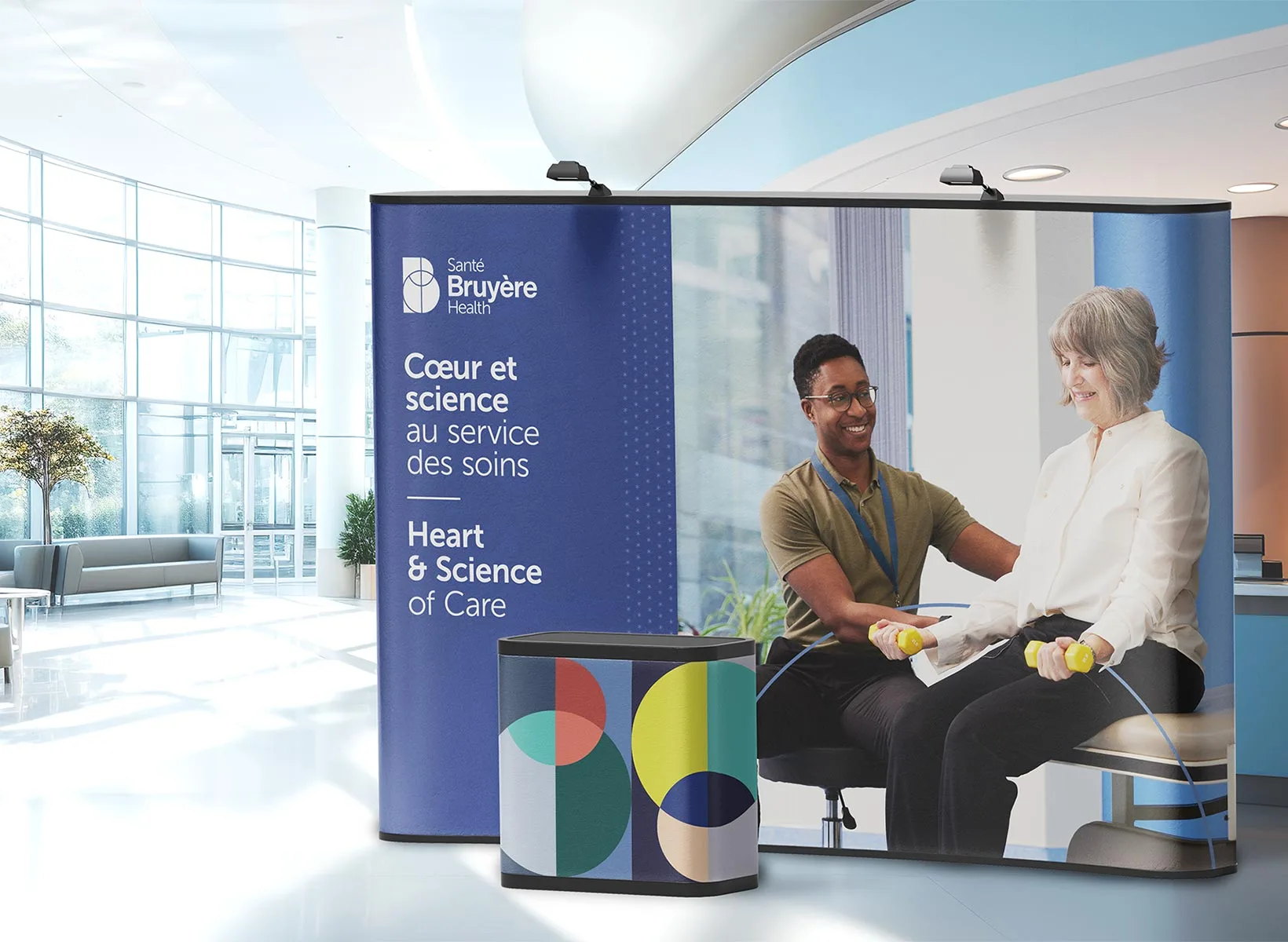 A display booth in a modern lobby shows a smiling healthcare provider assisting an older woman in physical therapy. The banner reads: “Heart & Science of Care” and “Cœur et science au service des soins.”.