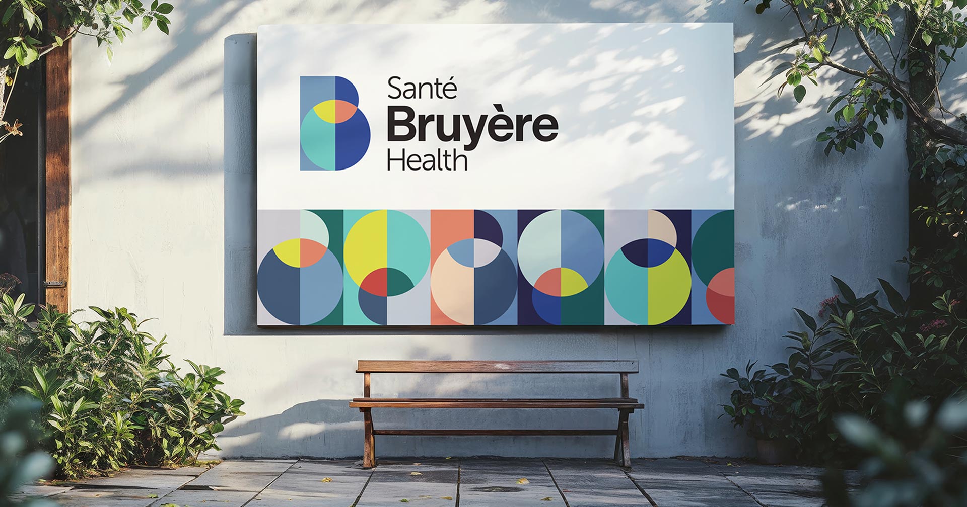 A large outdoor sign reads Santé Bruyère Health with colorful geometric shapes beneath the text. The sign is mounted on a wall above a wooden bench, surrounded by greenery and dappled sunlight.