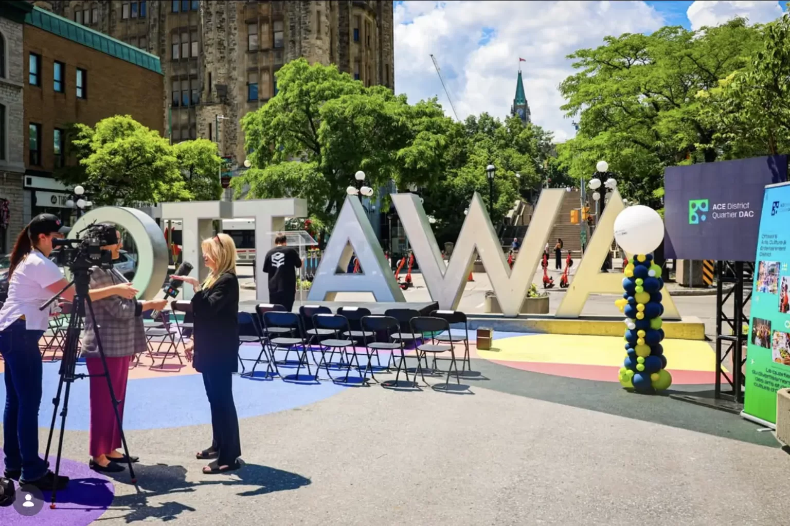 A group of people gathered around a large sign displaying the word "Ottawa."