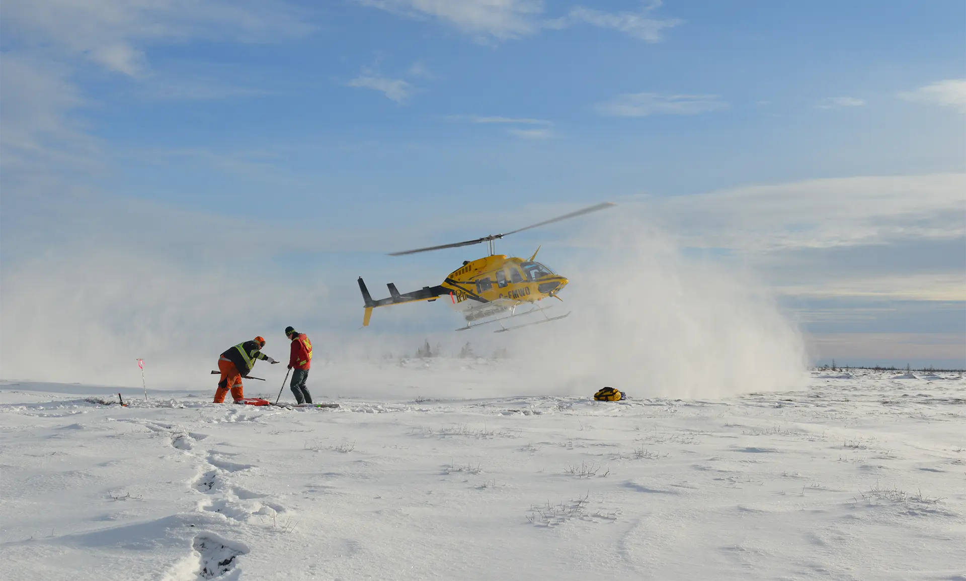 A helicopter hovers above a snow-covered field